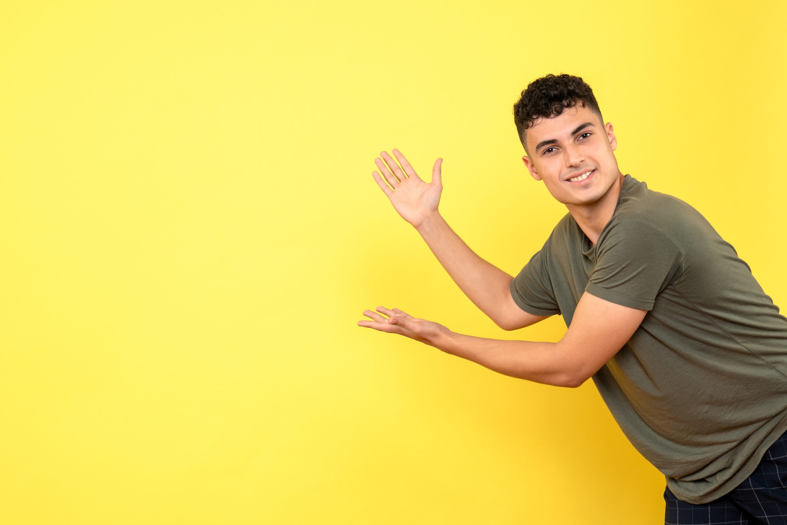 front view guy smiling guy points wall